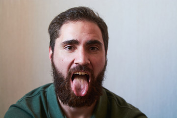 Portrait of young guy with dark beard with various emotions on his face in green shirt.