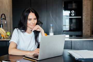 beautiful woman working with laptop and business documents on kitchen on self isolation