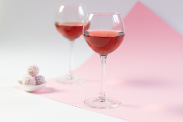 Rose wine glasses and sweet balls on white and pink background