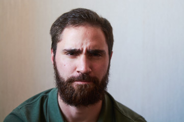 Fototapeta premium Portrait of young guy with dark beard with various emotions on his face in green shirt.