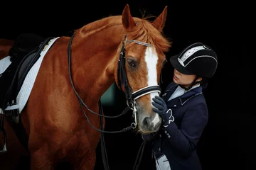 Fotobehang Portrait of a red dressage horse and young woman on black background. Girl with horse. Equestrian sport © matilda553