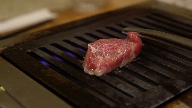Slow-motion of thinly sliced Japanese wagyu beef on grille for barbecue. Grill one of the best beef in Japan. Style Yakiniku meaning grilled meat cuisine. BBQ food.-Dan