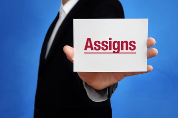 Assigns. Lawyer in a suit holds card at the camera. The term Assigns is in the sign. Concept for law, justice, judgement