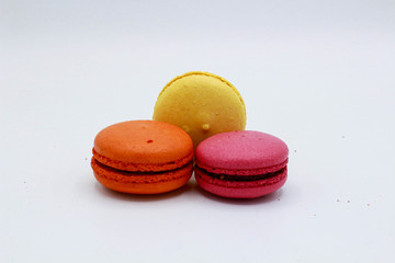 Pink, yellow and orange macarons. White background.