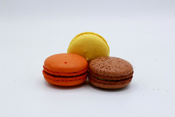 Yellow, brown and orange macarons. White background.