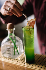 Paloma cocktail. Bartender decorates cocktail with a grapefruit slice.