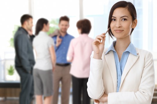 Portrait of smiling asian businesswoman in front of diverse business team.