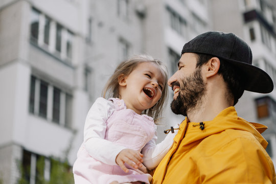 Portrait of a stylish pretty Father and his little daughter, they went for a walk on the playground in the courtyard of a multi-storey building
