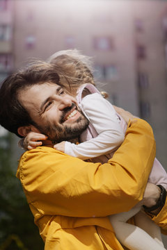 Portrait of a stylish pretty Father and his little daughter, they went for a walk on the playground in the courtyard of a multi-storey building