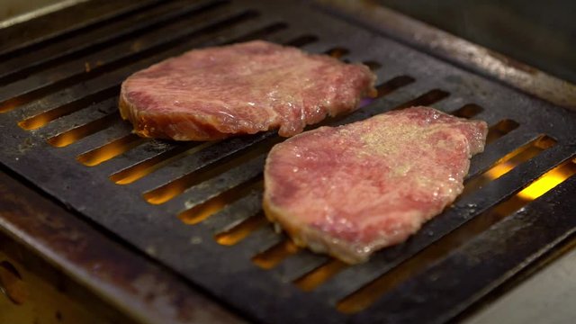 Slow-motion of thinly sliced Japanese wagyu beef on grille for barbecue. Grill one of the best beef in Japan. Style Yakiniku meaning grilled meat cuisine. BBQ food.-Dan