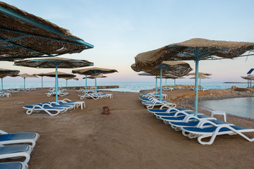 Beach coastline with deck chairs and umbrellas without people. Deserted resort.