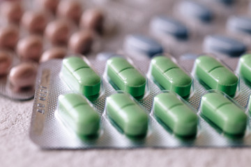 blisters of tablets of different colors - red, pink, green, blue pills and capsules