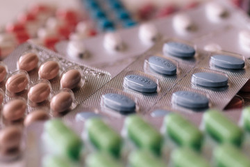 blisters of tablets of different colors - red, pink, green, blue pills and capsules