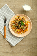 Plate of pasta with mushrooms in a creamy sauce with spinach on a linen tablecloth on a napkin and a fork.