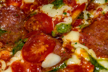 Pizza with salami, tomatoes, pesto and mozzarella. Close up.