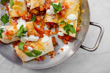 Mexican enchiladas topped with cheese, yoghurt sauce and coriander garnish. Vegetarian enchiladas made with lentils and red peppers. Mexican fast food. 