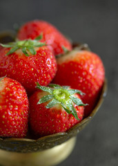 Fresh strawberry in a bowl on a dark table background. Close up of fresh strawberries in a bowl on the dark table.