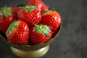 Fresh strawberry in a bowl on a dark table background. Close up of fresh strawberries in a bowl on the dark table.