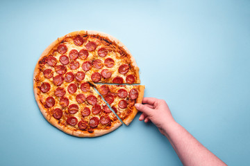 Grabbing a slice of pepperoni pizza top view.