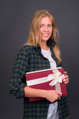 Portrait of happy young blond hipster woman holding gift box