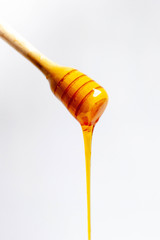 Honey dripping from a wooden dipper.