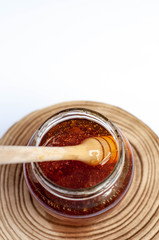 Wooden spoon drowning in to the glass jar with honey.