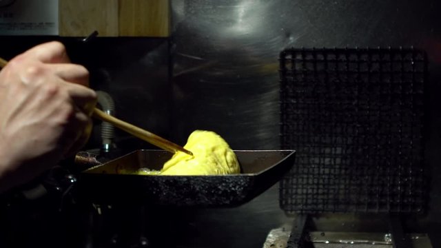 Slow Motion of tamagoyaki omelettes in metal pans at a street food market in downtown Tokyo. Popular Japanese street food in the izakaya restaurant.-Dan