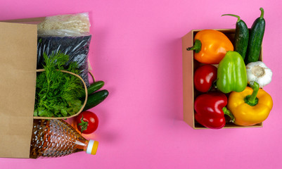 Flat lay. Paper bag with food supplies Quarantine food crisis isolated on pink background. Canned...