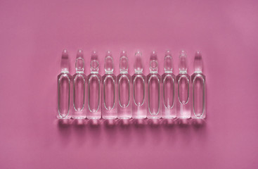 Ampoules for injections with medicine for coronavirus on a pink background. Vaccine for COVID-19. 