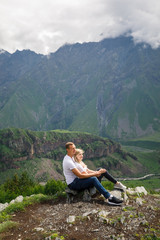 Naklejka na ściany i meble young beautiful couple travelers girl blonde in a white t-shirt, a man in a white t-shirt stand on a background of mountains in Georgia