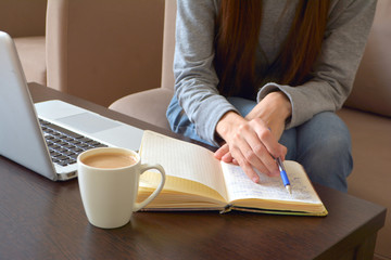 Online work or home education concept. Close up of a young female freelancer working on a laptop from a home office