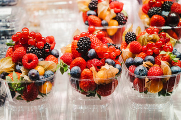 Fruit Salad arranged in plastic cups on a market stall with small fork inside, takeaway snack