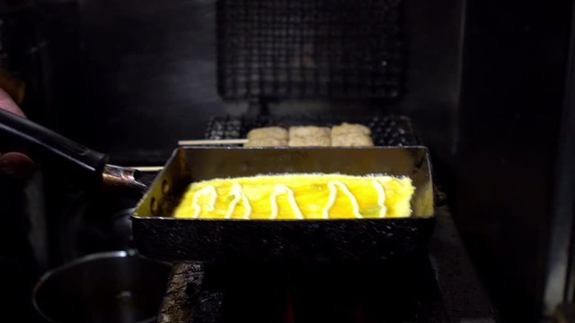 Slow Motion of tamagoyaki omelettes in metal pans at a street food market in downtown Tokyo. Popular Japanese street food in the izakaya restaurant.-Dan