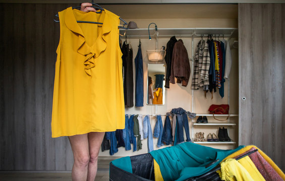 woman packing a suitcase trying on clothes wardrobe in background