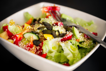 Vegetable Salad. Salad of tomato, cucumber, lettuce, sprinkled with sesame seeds. Salad in a white plate.