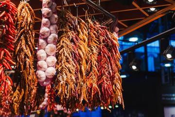 Red peppers, orange peppers, yellow peppers and garlic, hanged in the market