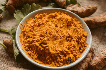 Turmeric roots and powder as background. Organic and healthy food. Close up view. 	
