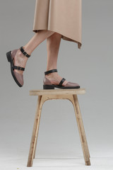 Legs in shoes of beautiful young woman standing on chair against plain wall, no brand, copy space