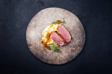 Traditional gourmet duck breast filet with mashed potatoes and orange sauce as top view on a rustic...