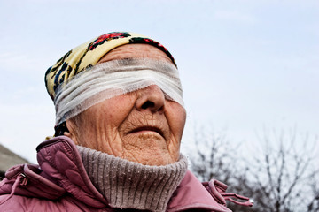 Close-up of an old grandmother with a blindfold. Controllable people conceptual photo. Blindfolded...