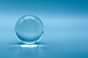 Fototapeta na wymiar Glass ball on blue background, glass globe ball