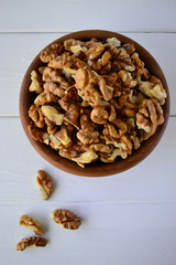 Hazelnuts in a wooden bowl on a white background.