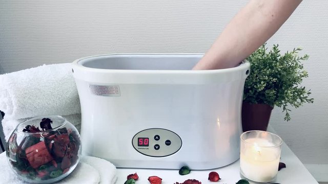 The process of paraffin therapy for hands in a spa salon.