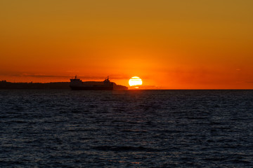 Cargo ship silhouette at Sunset in Oresund between Helsingor, Denmark and Helsingborg, Sweden.