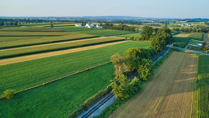 Aerial view of farm lands and corn crop with a train right of way in late afternoon