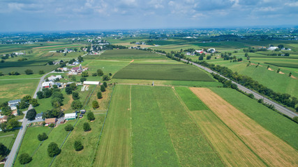 Fototapeta na wymiar Aerial view of farm lands in summer with blue skies and white fluffy clouds
