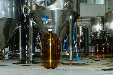 An empty plastic keg is standing inside the brewery against the backdrop of beer equipment.