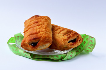 Two sweet cakes on a plate around the ribbon to measure the choice between a sweet and stoy diet slimming