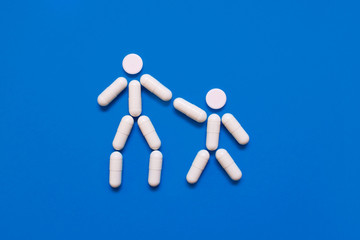 The shape of two little men from tablets on a blue background, the concept of treatment and protection against disease