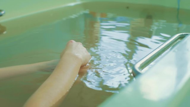 happy young woman relaxing in hot springs and using hand to bailing water,woman is lying in the bathroom,